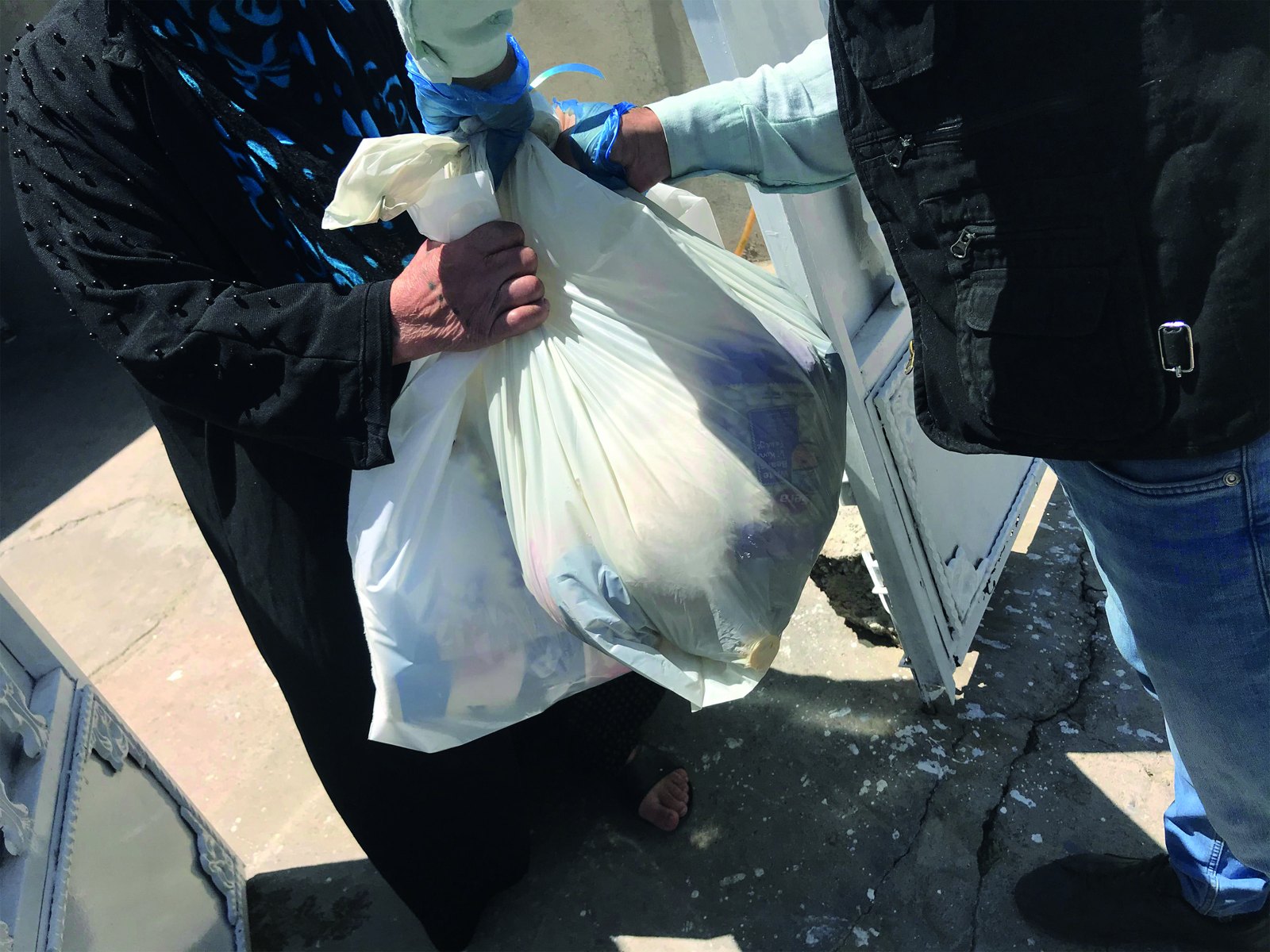 Hands passing a food parcel to a family at their home