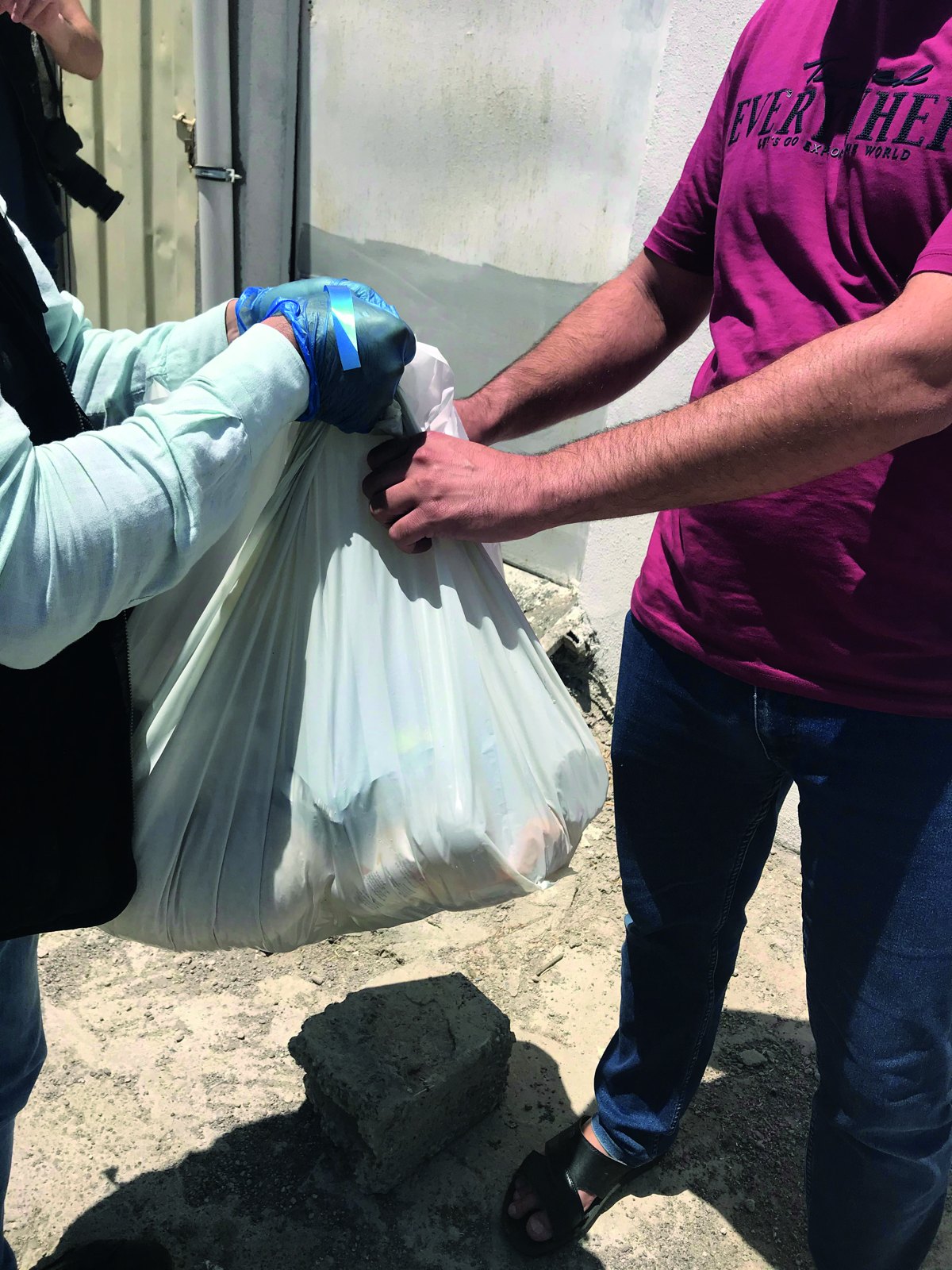 A volunteer hands a food basket to a family in Erbil