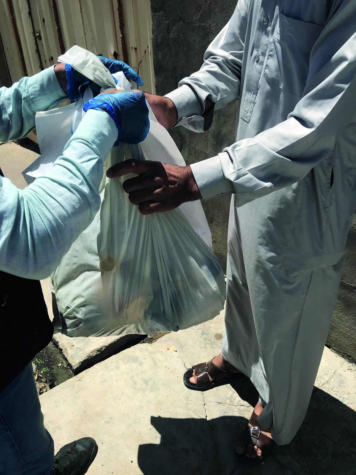 A volunteer passes a full aid bag to a resident